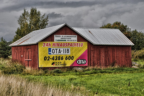 Iso ulkomainoskyltti ladon seinässä.